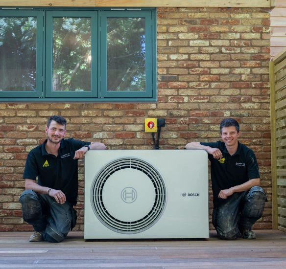 Apprentices next to heat pump